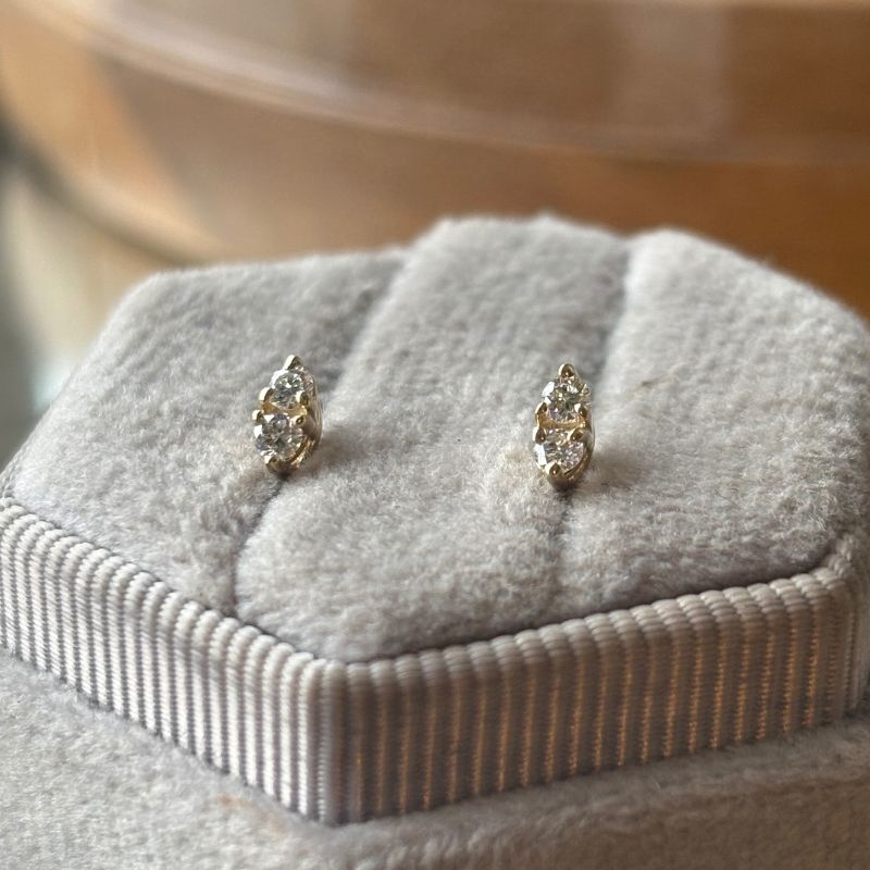 Triple prong double diamond earring on gray tray.