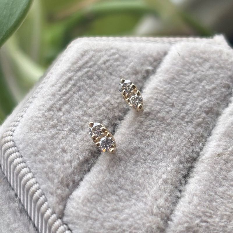 Triple prong double diamond earring on gray tray.