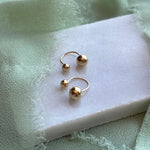 Alma 14kt yellow gold studs shown on a white marble tray with green linen draped around