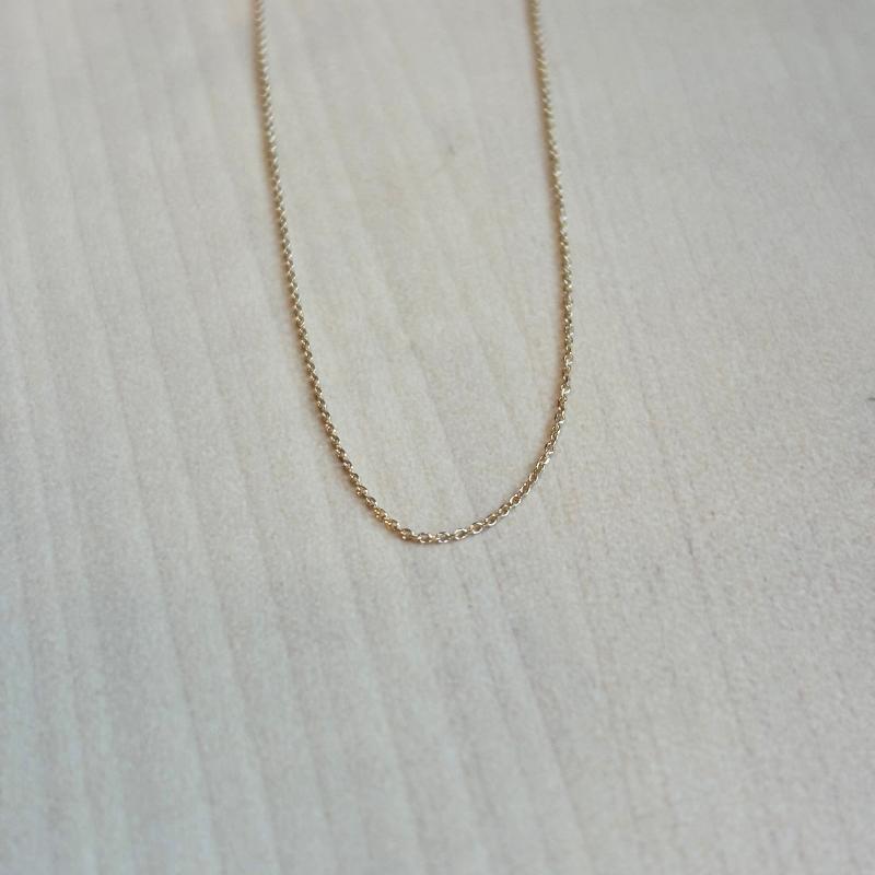 
                  
                    Load image into Gallery viewer, This beautiful and dainty 14 kt solid yellow gold chain is shown on a wooden background.
                  
                