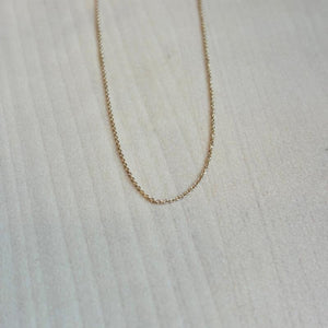 
                  
                    Load image into Gallery viewer, This beautiful and dainty 14 kt solid yellow gold chain is shown on a wooden background.
                  
                