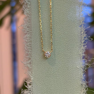 
                  
                    Load image into Gallery viewer, Bezel set diamond in 14kt yellow gold in front of green linen and white background.
                  
                