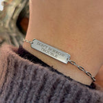 Sterling silver bar bracelet engraved and shown on the model's left wrist