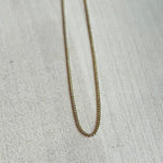 This 14 kt solid yellow gold chain is shown on wooden background.