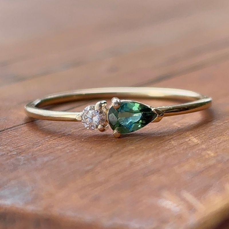 
                  
                    Load image into Gallery viewer, A petite pear tourmaline and round diamond ring shown on wooden table.
                  
                