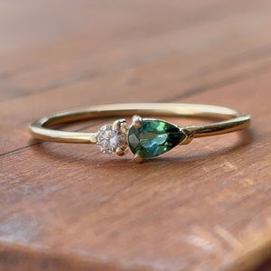 
                  
                    Load image into Gallery viewer, A petite pear tourmaline and round diamond ring shown on wooden table.
                  
                