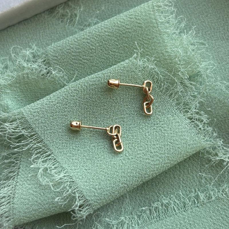 Side view of 14kt yellow gold chain studs shown on a blue-green linen.