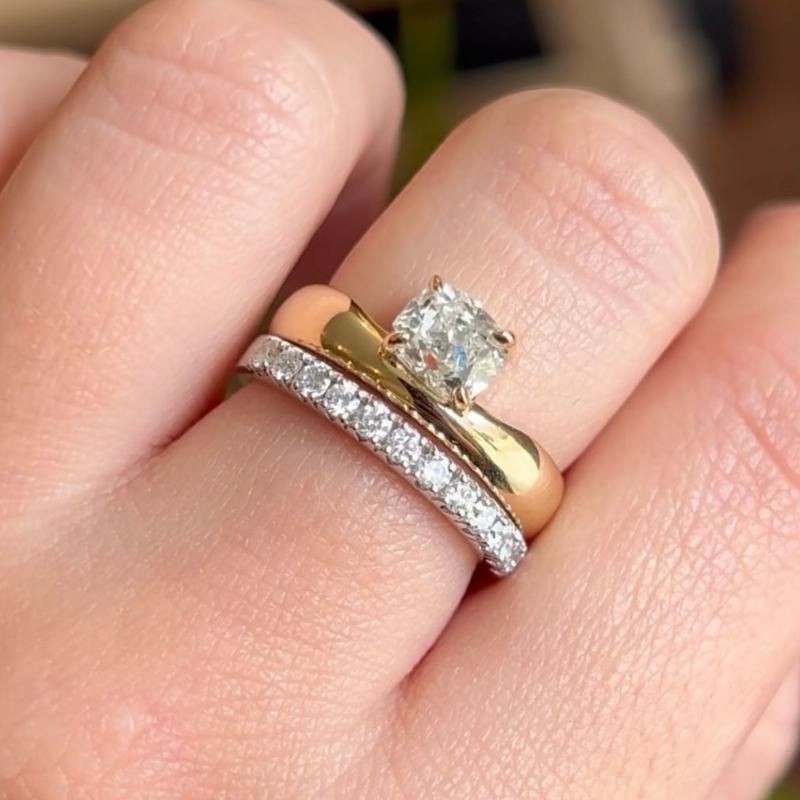 Image of an antique cushion-cut diamond set on a gold band and stacked with a diamond eternity ring.