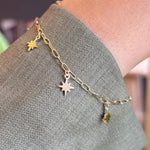 North star charm bracelet modeled on left wrist with green jacket sleeve.