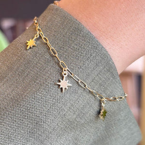 
                  
                    Load image into Gallery viewer, North star charm bracelet modeled on left wrist with green jacket sleeve.
                  
                