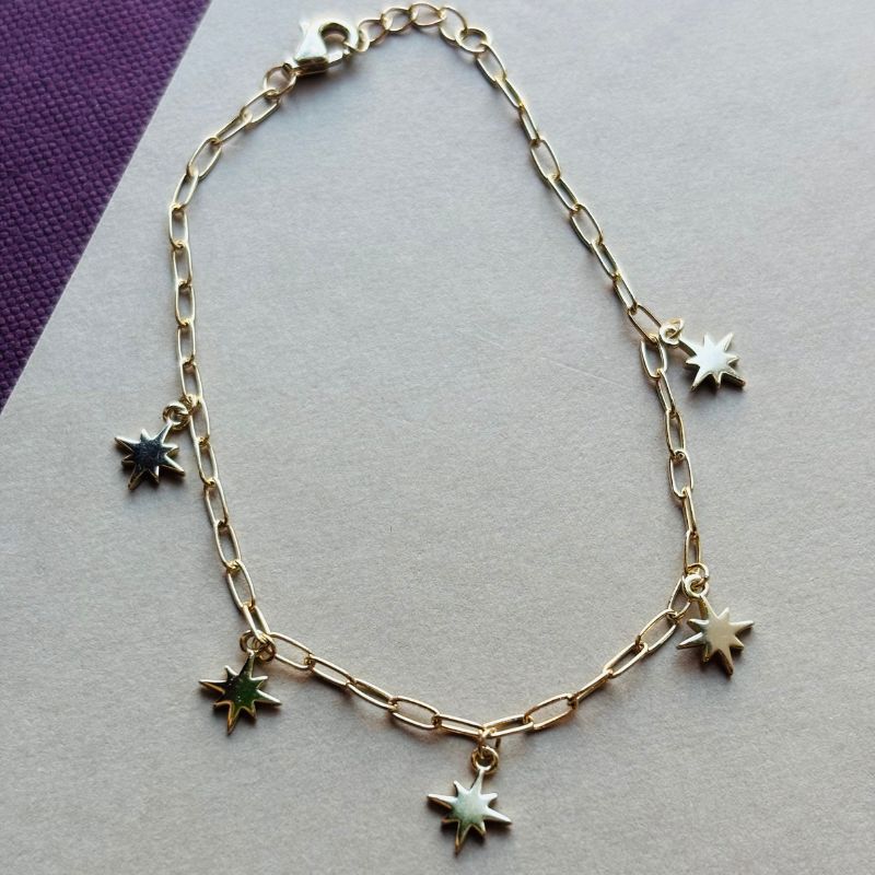 North star charm bracelet laid flat on a white and maroon book.