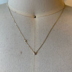 Diamond necklace with one petite bezel set diamond on chain shown in 14kt yellow gold on bust for scale.