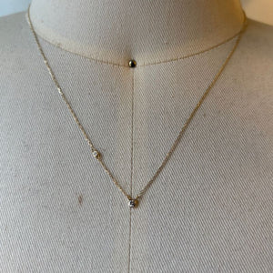 
                  
                    Load image into Gallery viewer, Diamond necklace with one petite bezel set diamond on chain shown in 14kt yellow gold on bust for scale.
                  
                