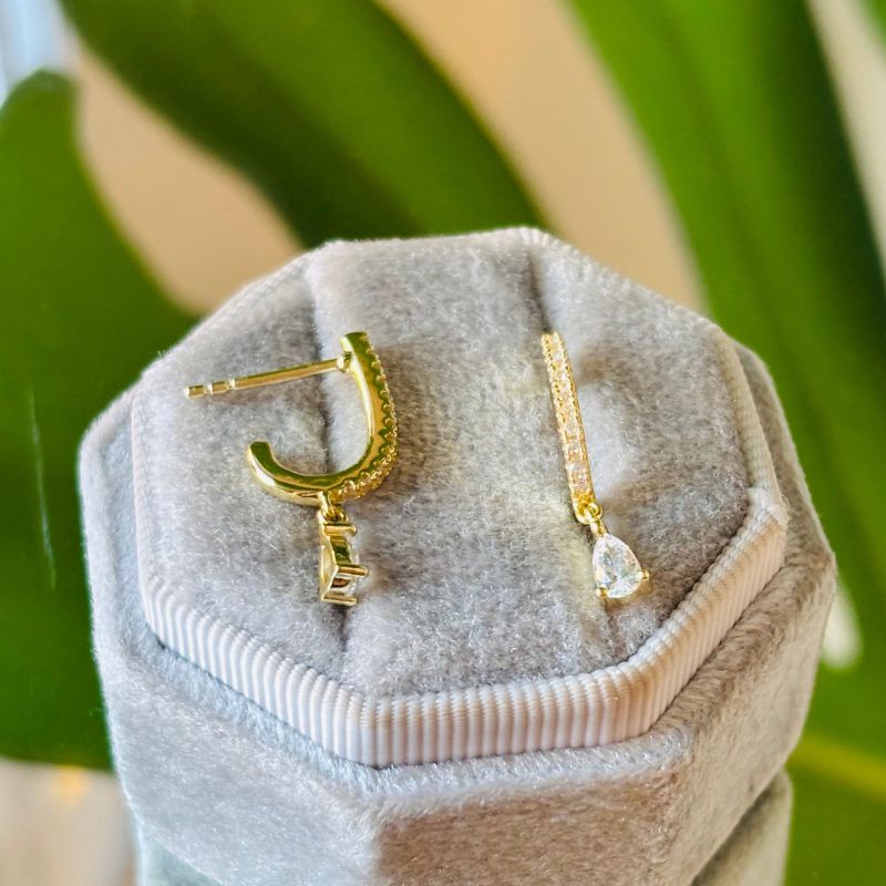 Yellow gold crystal studded style drop studs with a pear hanging crystal are on a gray velvet tray.