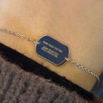 Engraved sterling silver dog tag bracelet shown on model's left wrist.