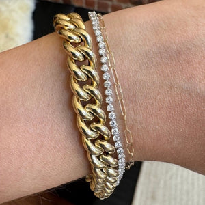 
                  
                    Load image into Gallery viewer, A large gold curb chain, round tennis bracelet cast in white gold and dainty, gold paperclip bracelet on the wearer&amp;#39;s wrist for scale.
                  
                