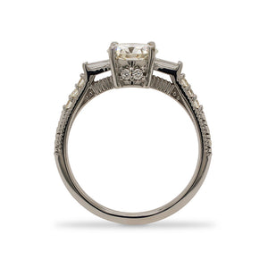 
                  
                    Load image into Gallery viewer, Side view of a round cut diamond engagement ring made of 14 kt white gold with baguette and round cut diamonds going down the shank and two additional round cut diamonds on the side.
                  
                