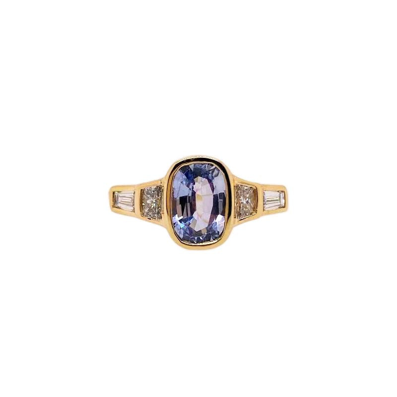 Casted in 14 kt gold, this light blue oval sapphire center stone is flanked by four trapezoid and baguette cut and diamonds. This bezel set ring is low profile and is perfect as an engagement ring.