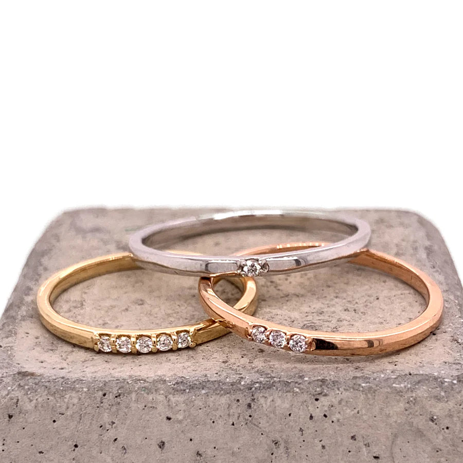 
                  
                    Load image into Gallery viewer, 14 Kt white gold staking band with single diamond , 14 Kt rose gold band with three diamonds, and 14 Kt yellow gold band with five diamonds on a concrete cube.
                  
                