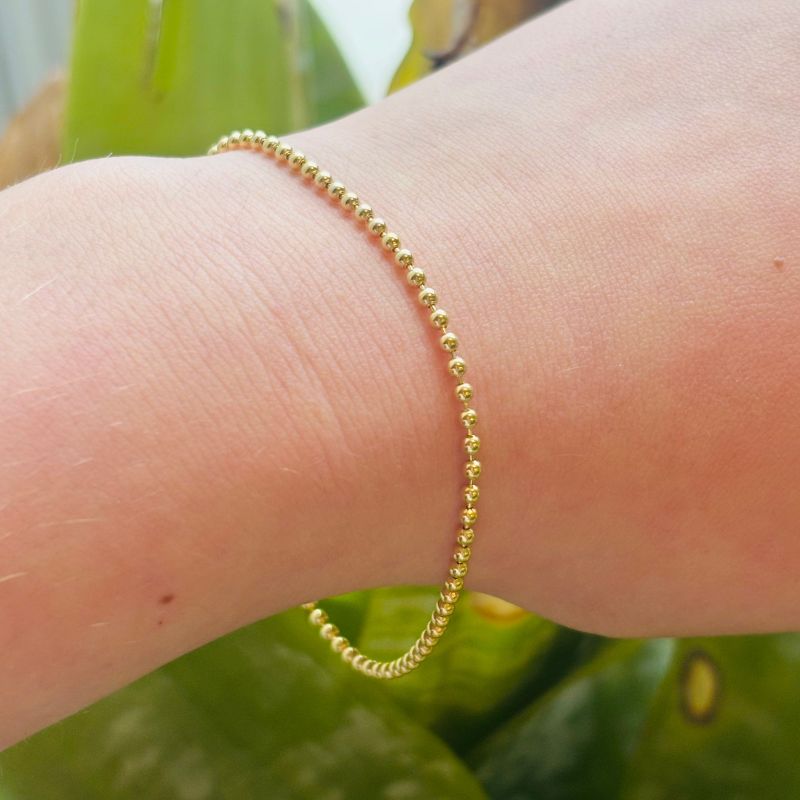 Small ball 14kt yellow gold bracelet modeled on left wrist